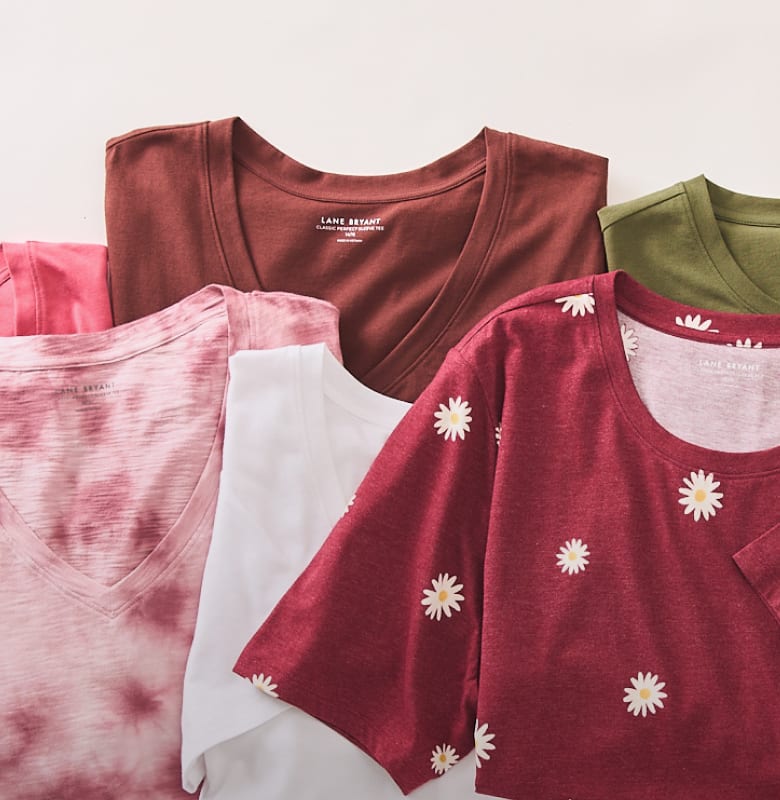A collection of colorful t-shirts, including a pink tie-dye, a white, a maroon floral, and a brown v-neck, are neatly folded in the foreground, with a green t-shirt peeking out in the background.