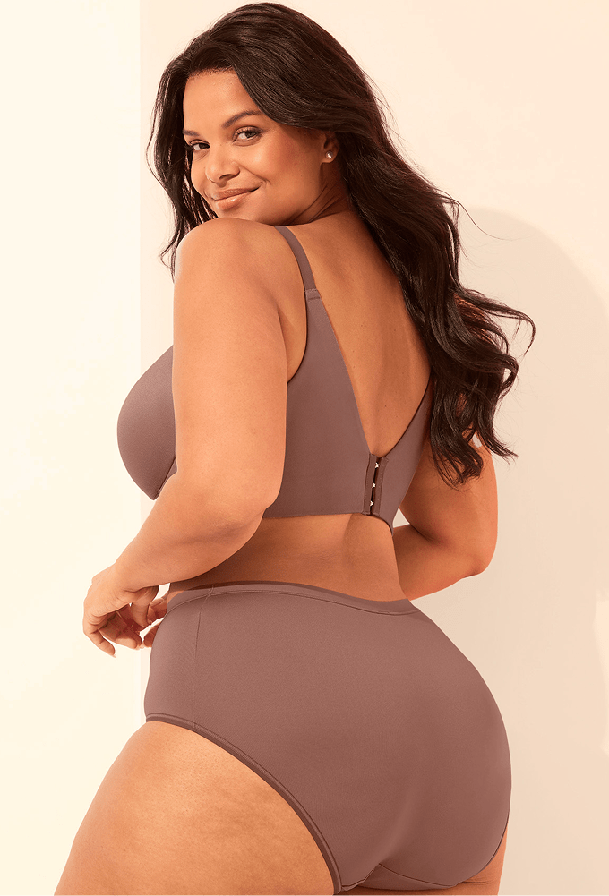 A woman in a mauve bra and high-waisted underwear poses against a plain, light-colored background.