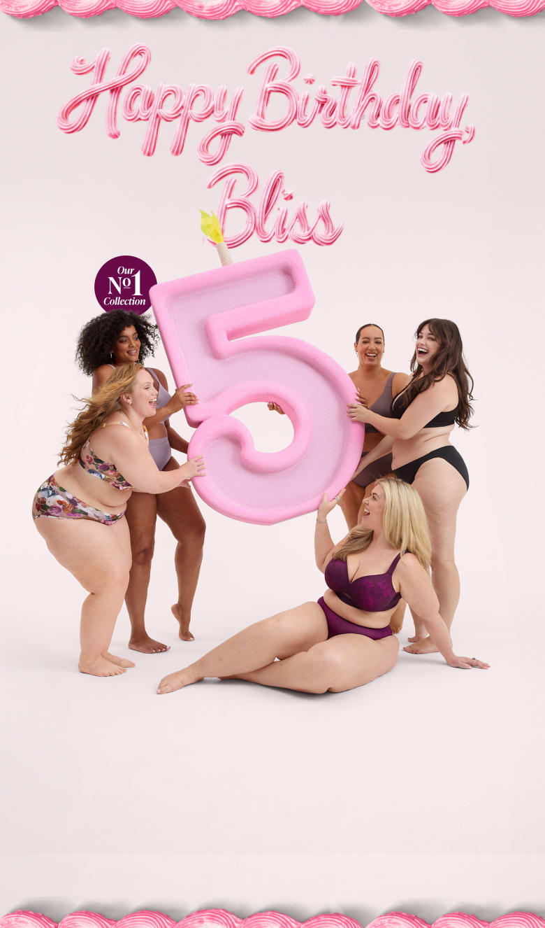 Five women in lingerie celebrate a 5th birthday with a large pink number five candle and Happy Birthday Bliss text against a light pink background.