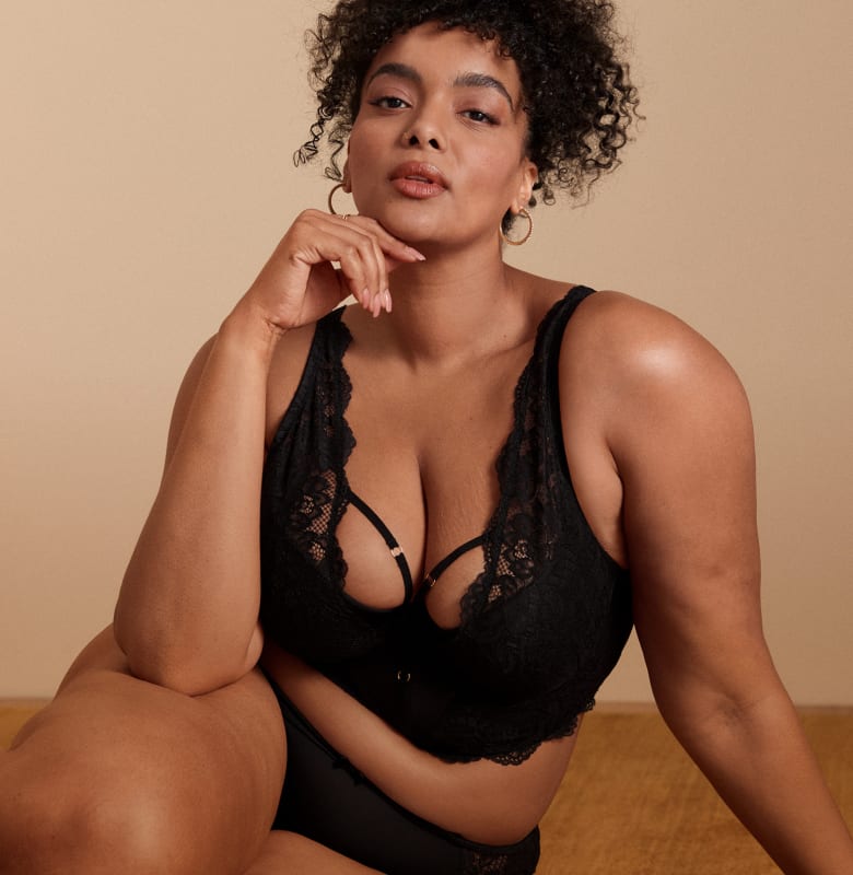 A woman in a black lace bra and underwear poses against a plain, light-colored background.