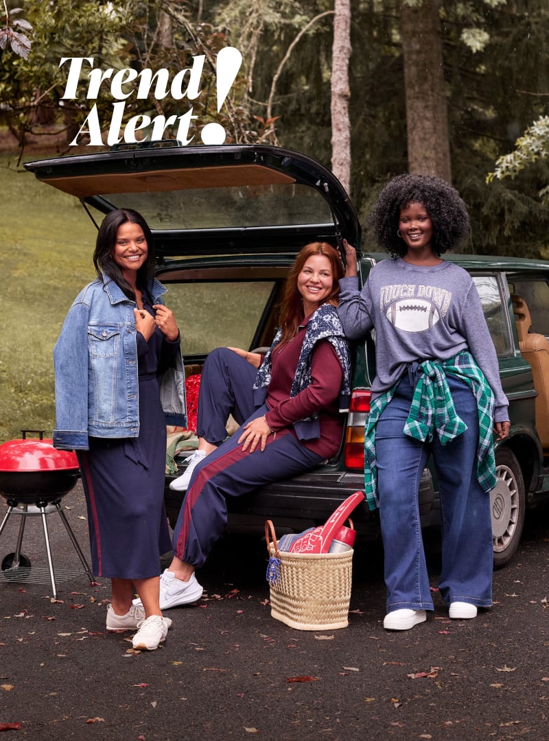 hree women pose in front of an open car trunk with a grill and picnic basket in the foreground, set against a backdrop of trees.