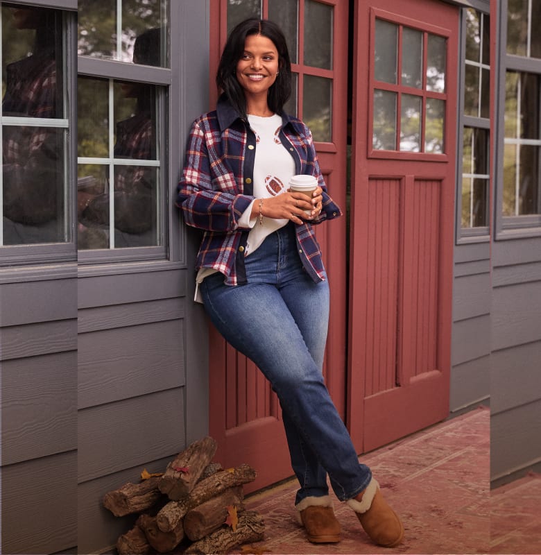 A woman in jeans poses by a rustic cabin and in an orchard with a ladder and apples.