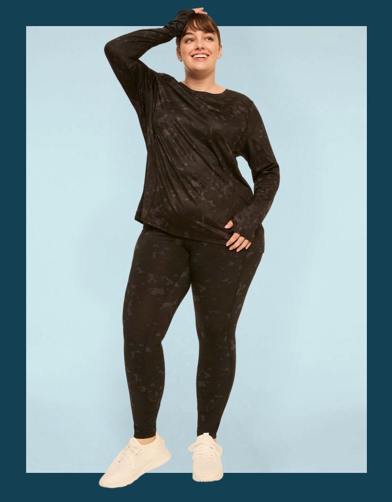 A woman in a black patterned athletic set stands against a light blue background.