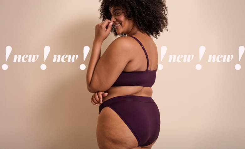 A smiling woman with curly hair wearing purple lingerie stands against a plain beige background with the word 'new!' repeated across the center.