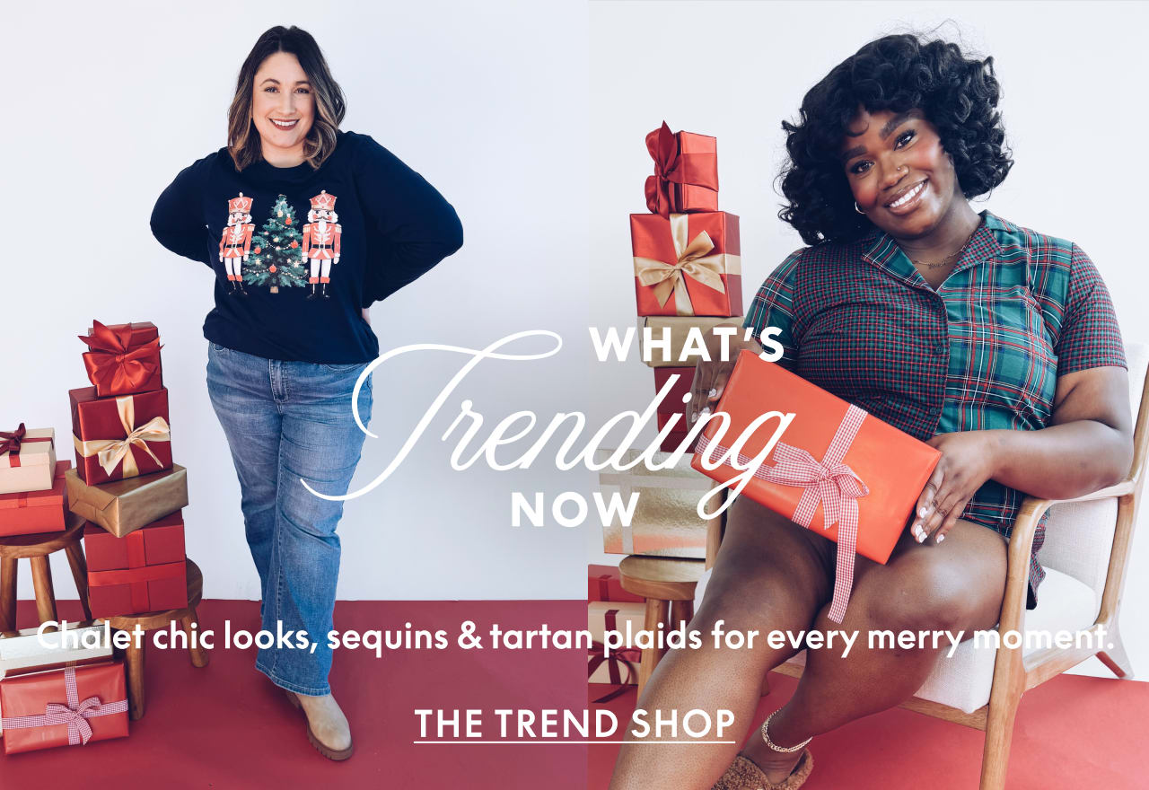 Two women pose with wrapped gifts against a plain white background and red flooring.