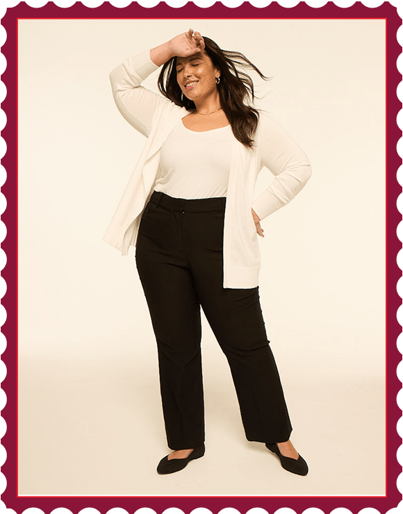 A woman in a white top, black pants, and a cream cardigan poses with her hand on her forehead against a plain, light-colored background.