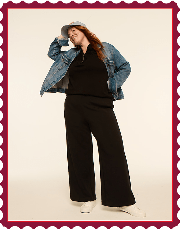 A woman in a denim jacket and black loungewear poses against a plain, light-colored background.