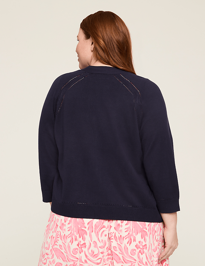 The image shows the back view of a person wearing a navy blue sweater and a pink and white patterned skirt, standing against a plain white background.