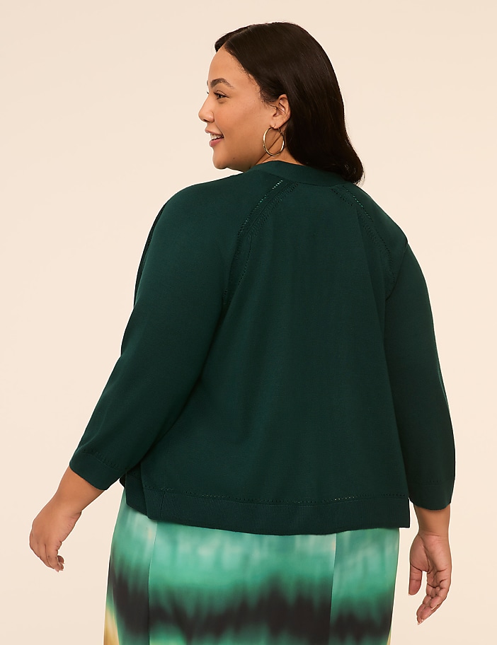 The image shows a woman wearing a dark green top with puffed sleeves, and a tie-dye skirt in shades of green. She is standing against a plain background.