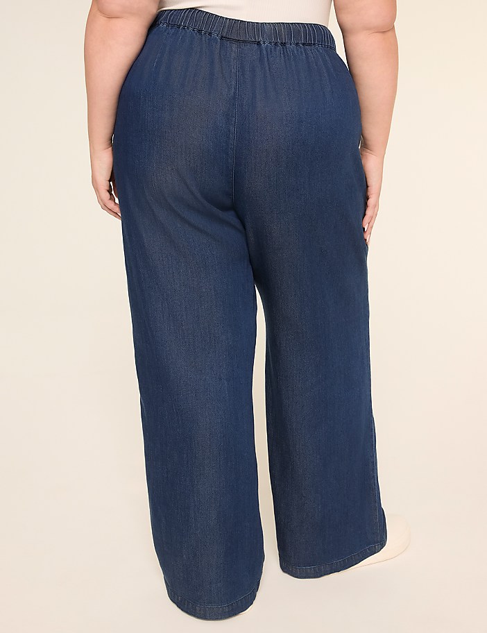 The image shows a pair of loose, dark denim pants with an elastic waistband, worn by a person with a larger body type.