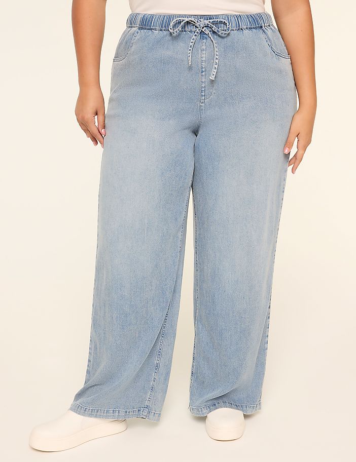 The image shows a pair of light blue, wide-leg denim pants with a drawstring waist, worn by a person's lower body.