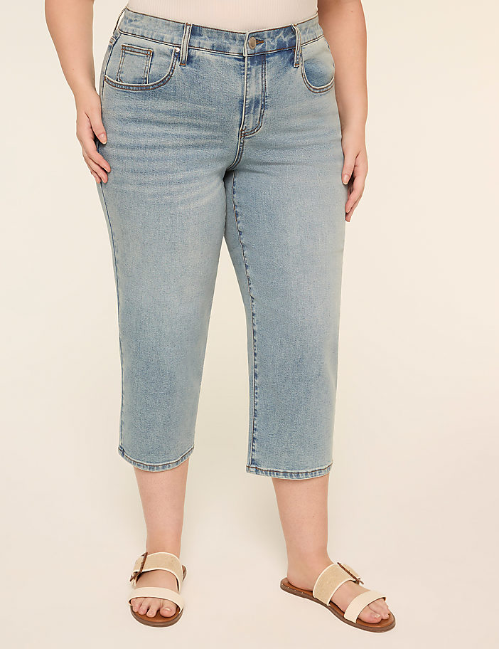 The image shows a pair of light-colored denim shorts or capri pants worn with a pair of beige sandals on a plain background.