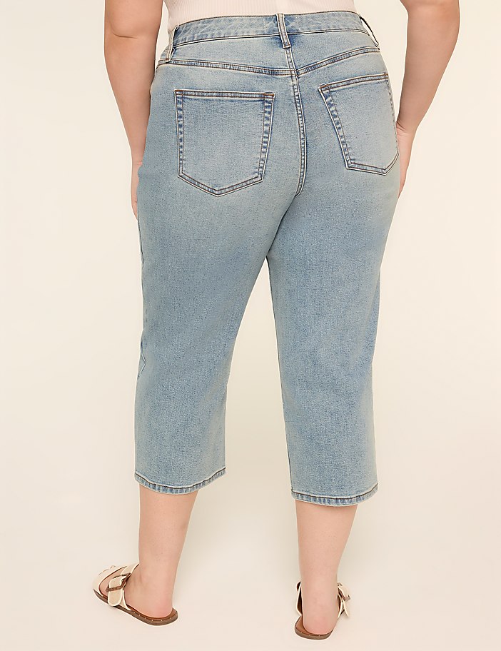 The image shows a pair of light-colored denim capri pants with pockets on the back, worn by a person standing against a plain background.