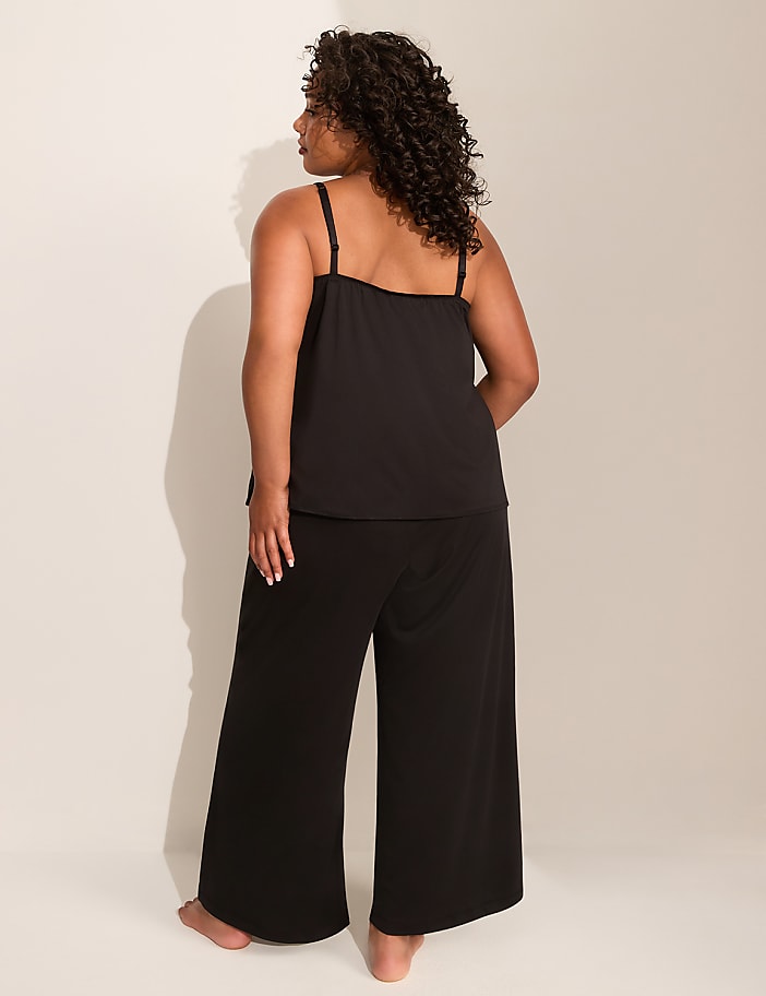 A woman in black pajamas stands with her back to the camera against a plain, light-colored background.
