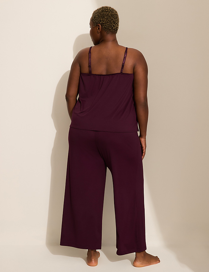 A person in a plum-colored pajama set stands with their back to the camera against a plain, light-colored background.