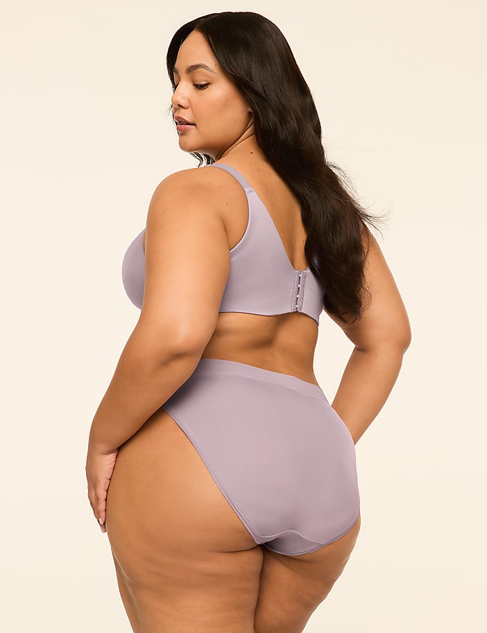 A woman in a lavender bra and underwear stands against a plain, light-colored background.