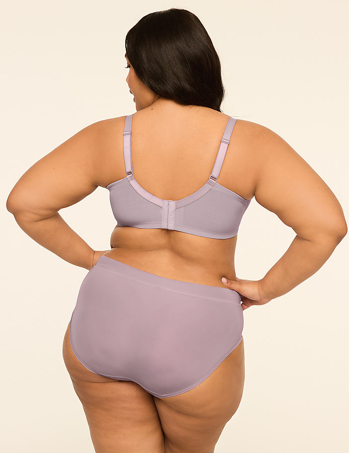 A woman in a lavender bra and underwear stands with her back to the viewer against a plain, light-colored background.