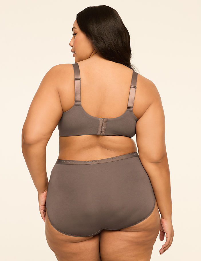 A woman in a grey bra and underwear stands against a plain, light-colored background.