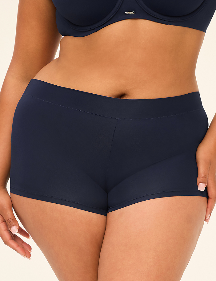 A woman in navy blue underwear stands against a plain, light-colored background.