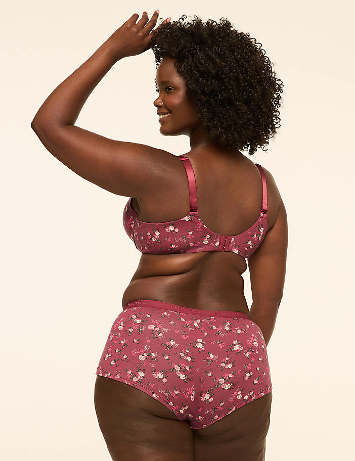 A woman in a floral bra and matching underwear is shown from the back against a plain, light-colored background.