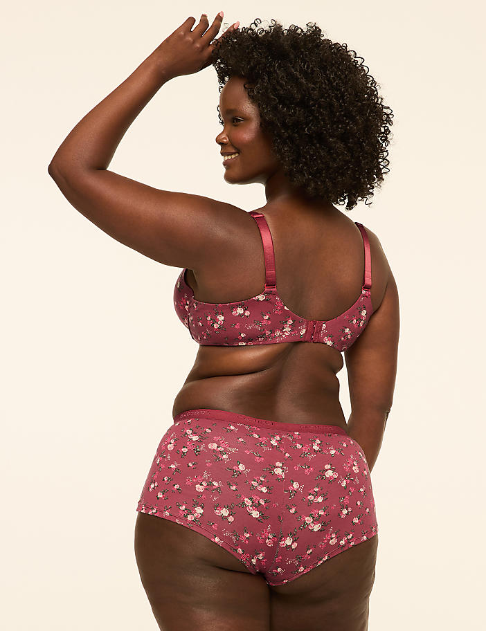 A woman in a floral bra and shorts stands against a plain, light-colored background.