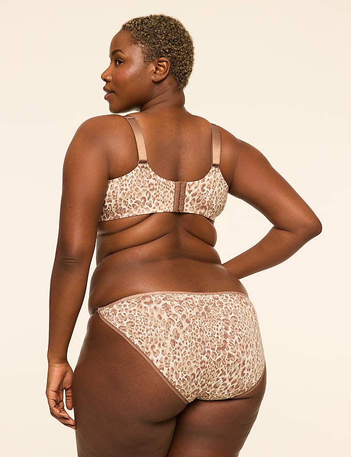 A woman in a leopard-print bra and underwear stands against a plain, light-colored background.