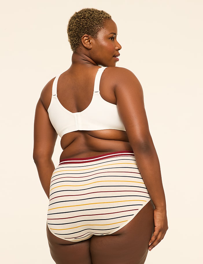 A woman with short, blonde hair is shown from the back, wearing a white bra and striped underwear, against a plain, light-colored background.