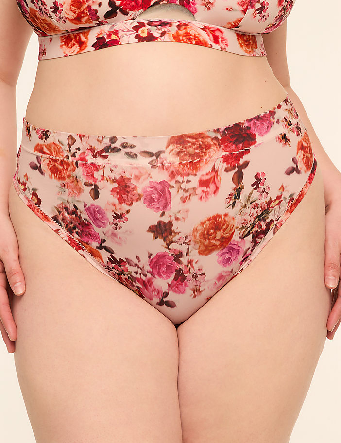 A person wears floral-patterned underwear in the foreground, against a plain, light-colored background.