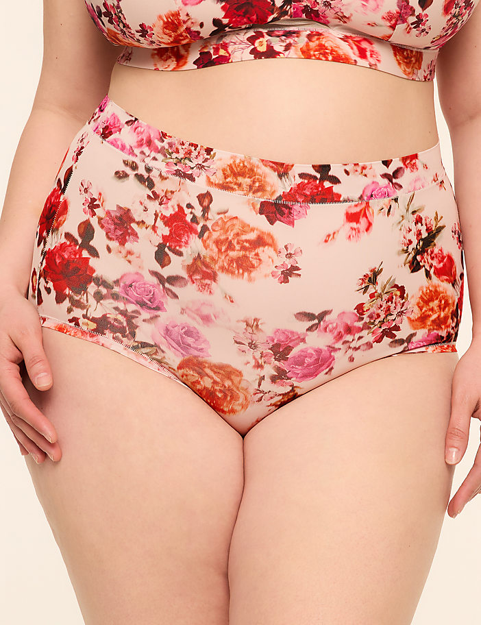 A person is wearing floral-patterned underwear and a matching bra against a plain background.