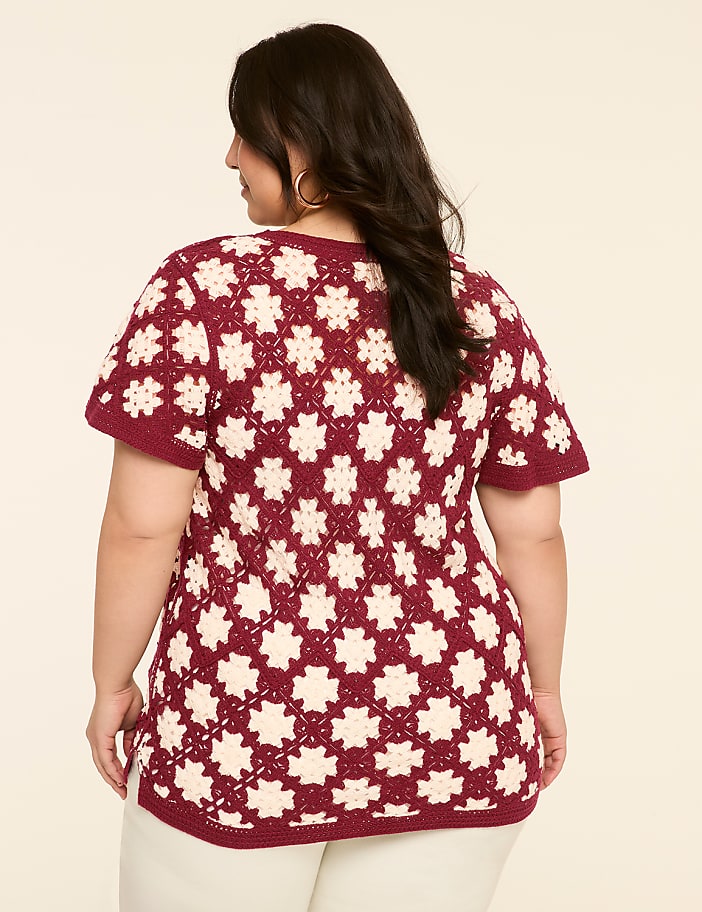 A woman in a maroon and cream crocheted top stands against a plain, light beige background.