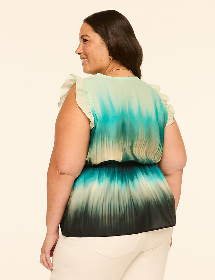 A woman in a tie-dye top stands against a plain, light-colored background.
