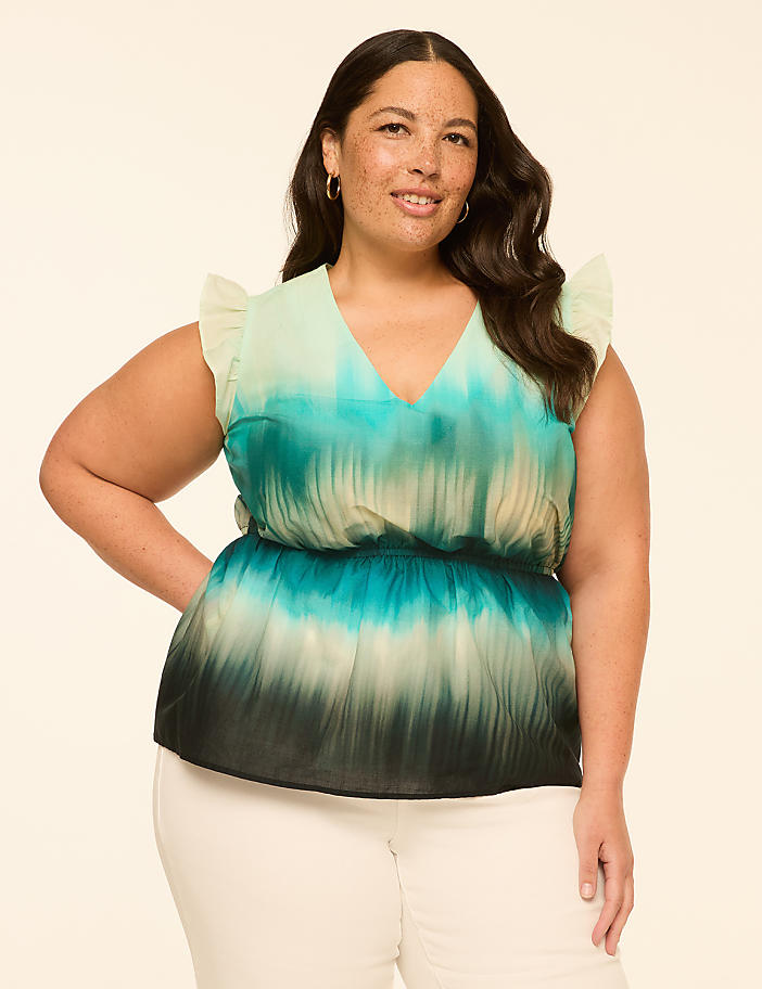 A woman in a tie-dye top stands against a plain, light-colored background.