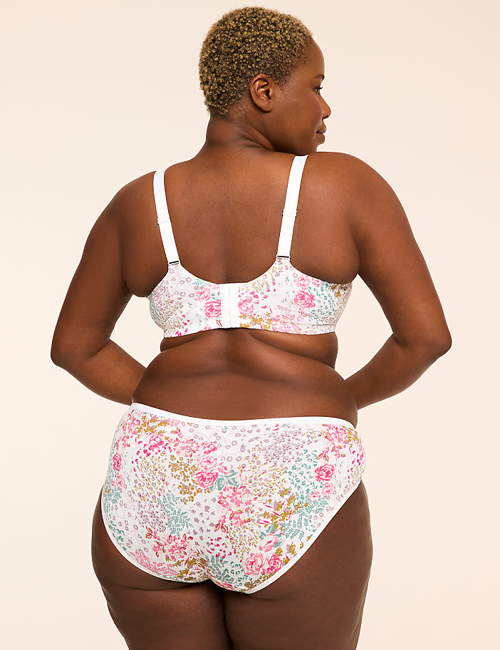 A woman with short blonde hair is shown from the back, wearing a floral bra and matching underwear against a plain, light-colored background.