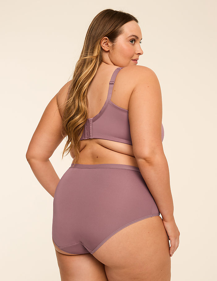 A woman in a mauve bra and high-waisted briefs is shown from the side against a plain, light-colored background.
