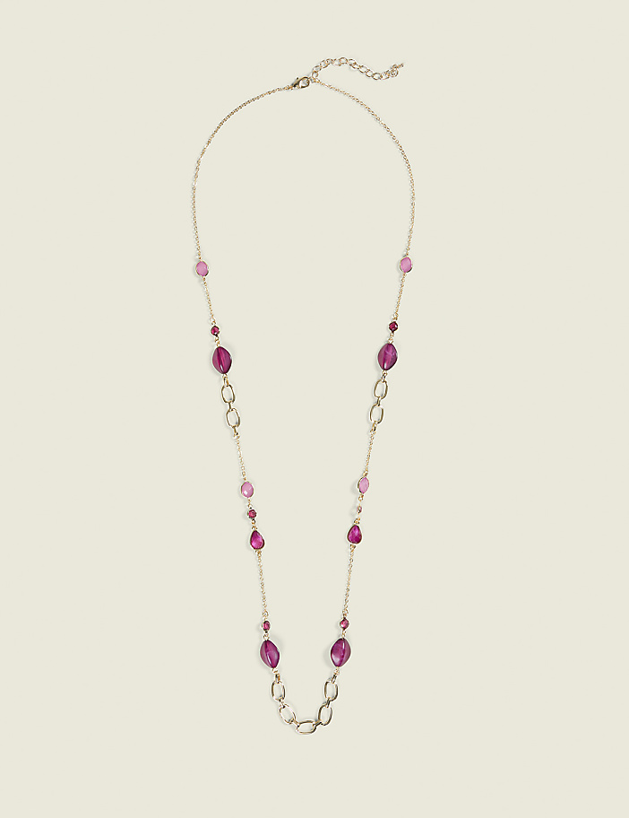A long, gold-toned necklace with various shades of pink and purple beads and oval links is laid out against a plain, light beige background.