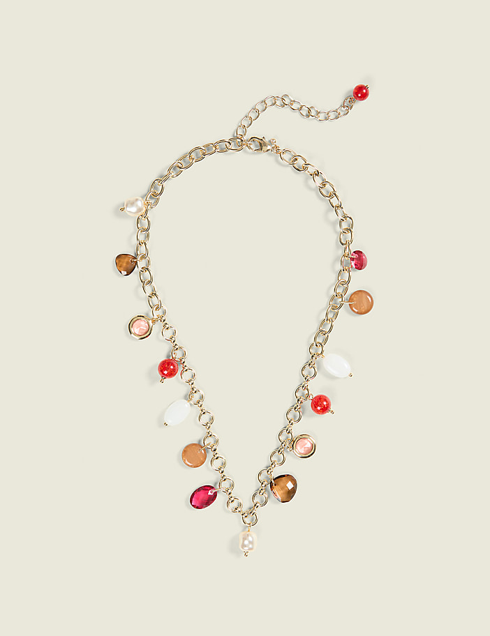 A gold chain necklace with colorful beads and charms hangs against a plain, light-colored background.