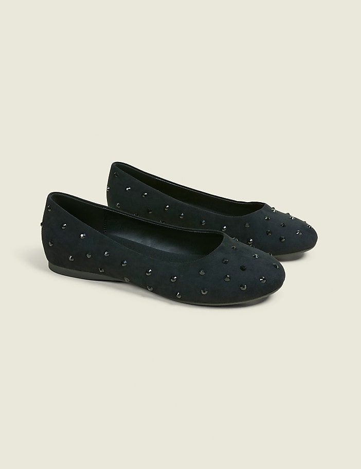 A pair of black studded ballet flats rests on a light beige background.