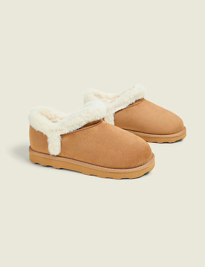 A pair of tan, fuzzy-lined slippers rests on a plain, light gray background.