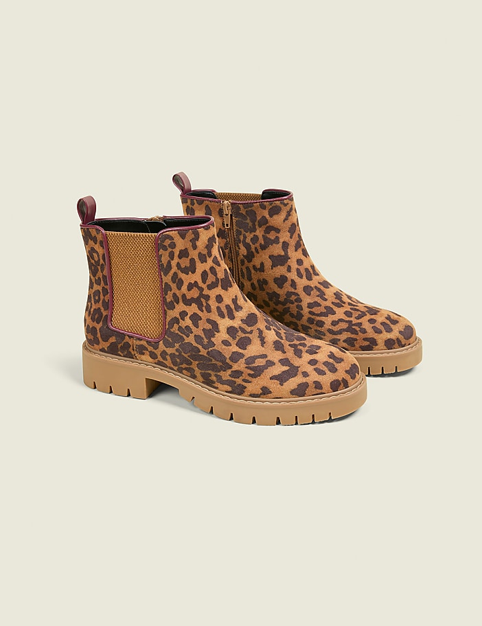 A pair of leopard-print Chelsea boots with thick soles rests on a plain, light-colored background.