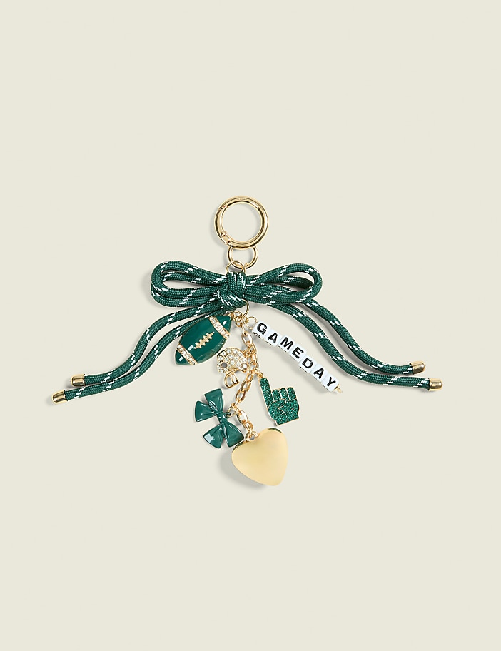 A green and white striped ribbon bow holds a collection of football-themed charms, including a football, a lucky clover, a foam finger, and a heart, against a plain cream background.