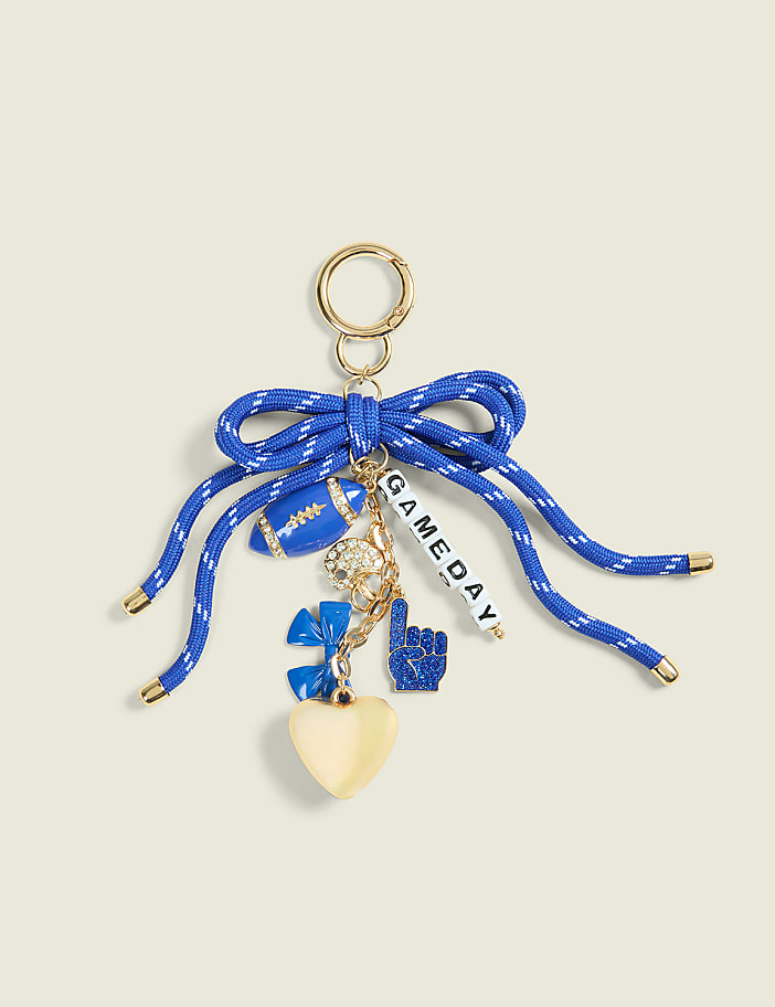 A blue ribbon bow with football-themed charms hangs from a gold keyring against a pale yellow background.