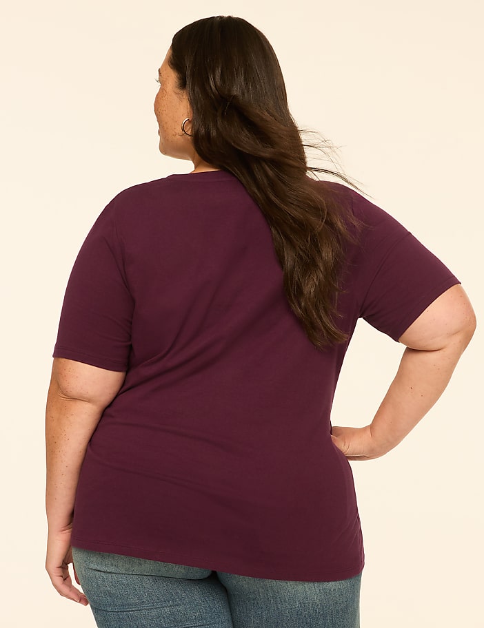 A woman in a maroon t-shirt and jeans stands with her back to the viewer against a plain, light-colored background.