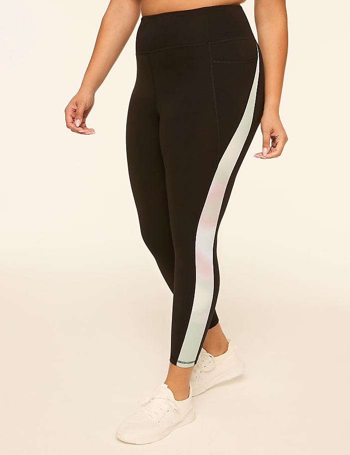 A person in black leggings with a pastel stripe down the side stands against a plain, light-colored background.