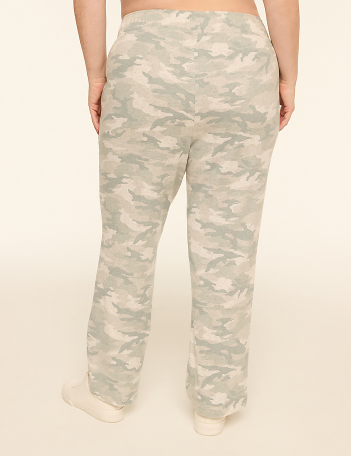 A person wearing camouflage pants stands against a plain, light-colored background.