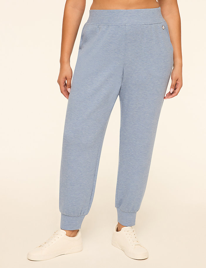 A person wearing light blue sweatpants and white sneakers stands against a plain, light-colored background.