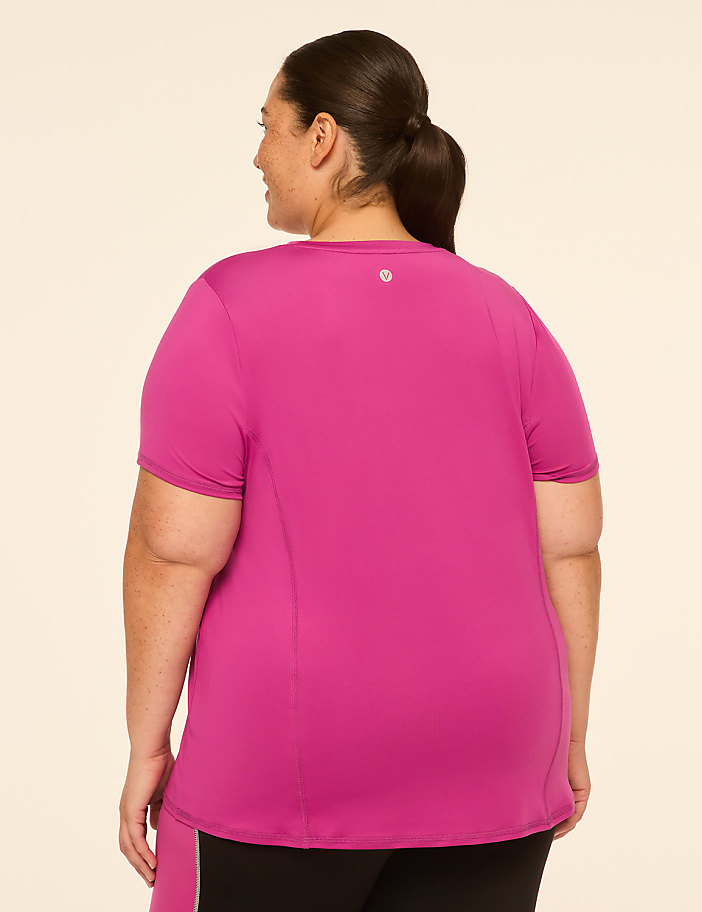 A woman in a bright pink t-shirt stands against a plain, light-colored background.