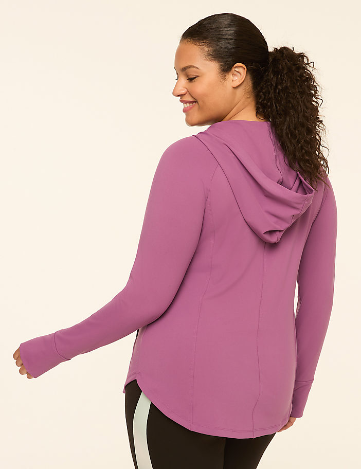 A woman in a purple hooded jacket with thumbholes stands against a plain, light-colored background.