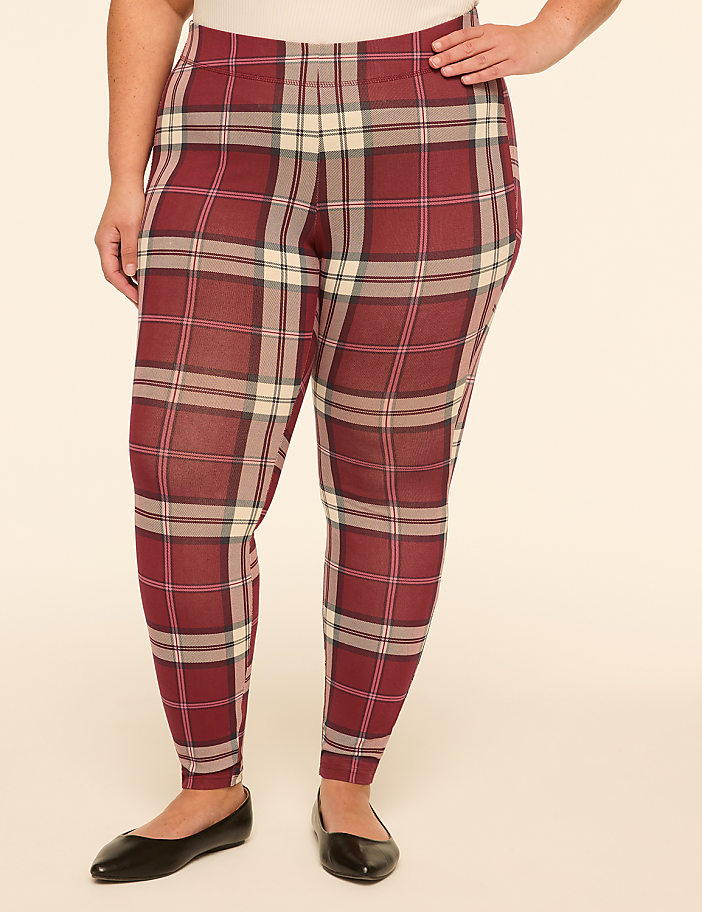 A person wearing red plaid leggings and black ballet flats stands against a plain, light-colored background.