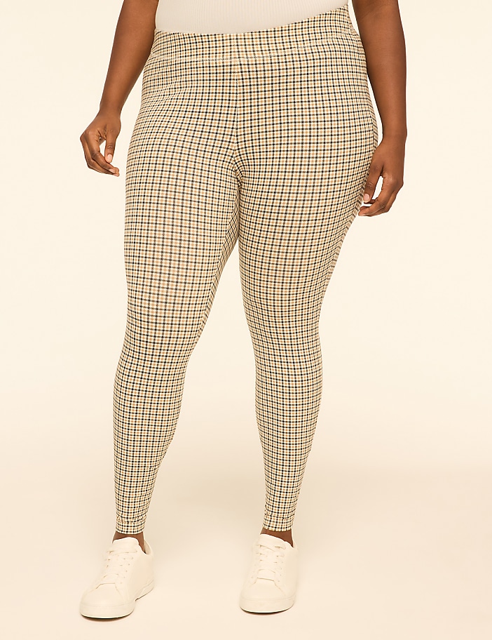 A person wearing plaid leggings and white sneakers stands against a plain, light-colored background.