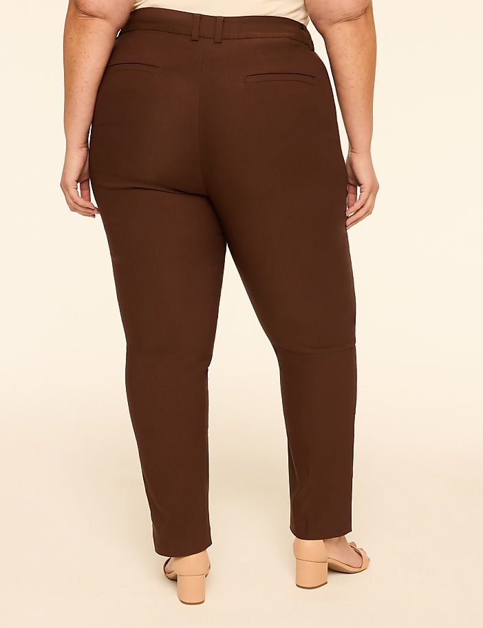 A person wearing brown pants and light-colored sandals stands against a plain, light-colored background.